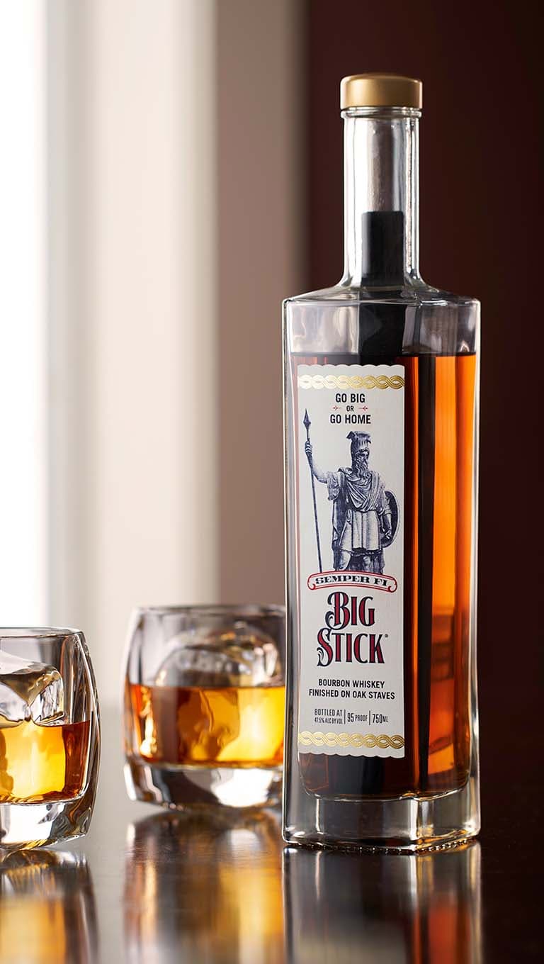 A Big Stick bourbon bottle alongside two shot glasses