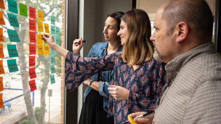 a group of people standing in front of a SCRUM board