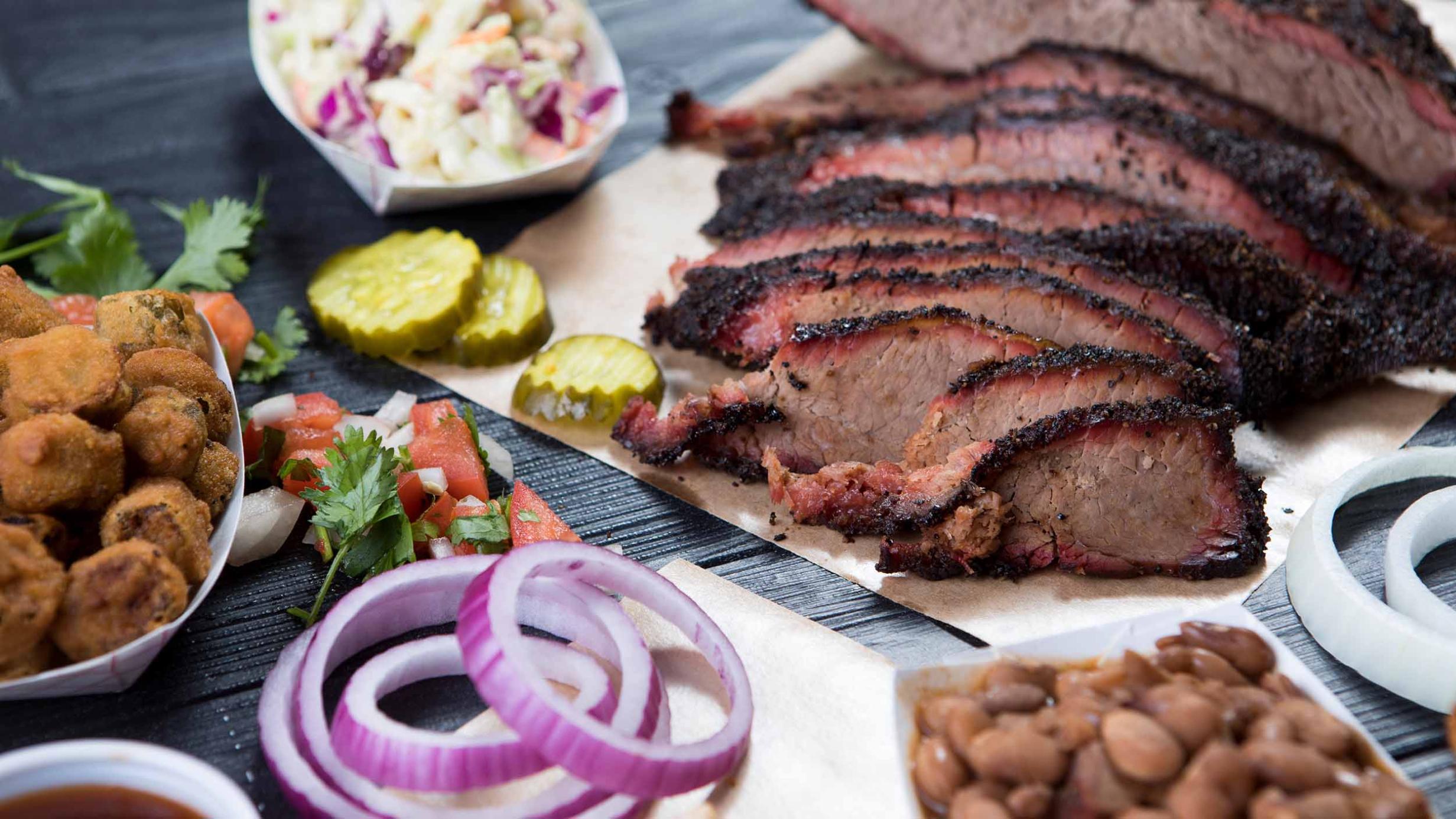 A table set with sliced steak and various sides and seasonings